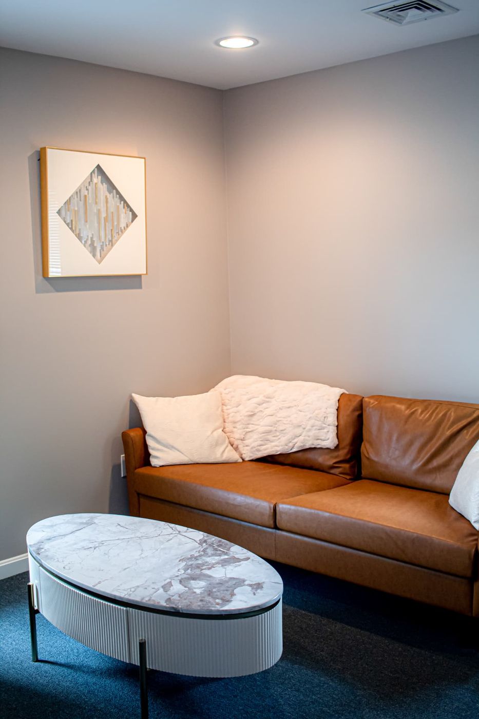 A calm Compass of Hope office with a leather sofa, soft pillows, and a marble table